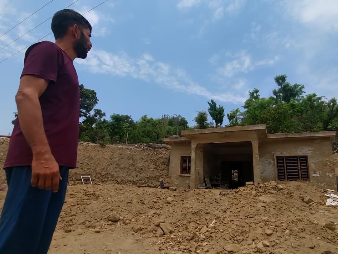 बाढ़ से मलबे में दबे अपने आशियाने को देखता भेड़ बलोड़ गांव का करण सिंह