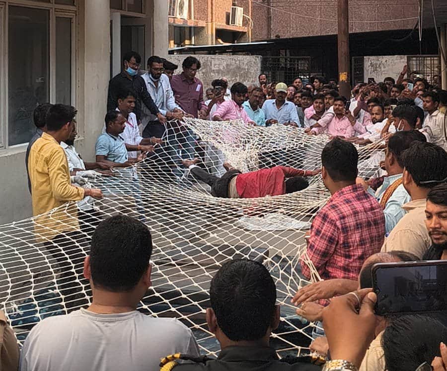 मेडिकल कॉलेज की छत से कूदे युवक को जाल लगाकर बचाते कर्मचारी व दमकलकर्मी। संवाद
