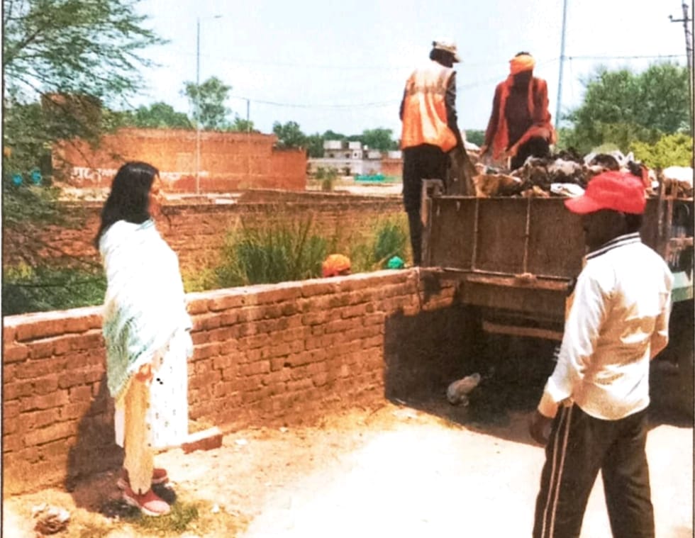 मंझनपुर के वार्ड नंबर 08 महात्मा गांधी नगर में फैले कूड़े को उठवातीं ईओ प्रतिभा सिंह। स्रोत: स