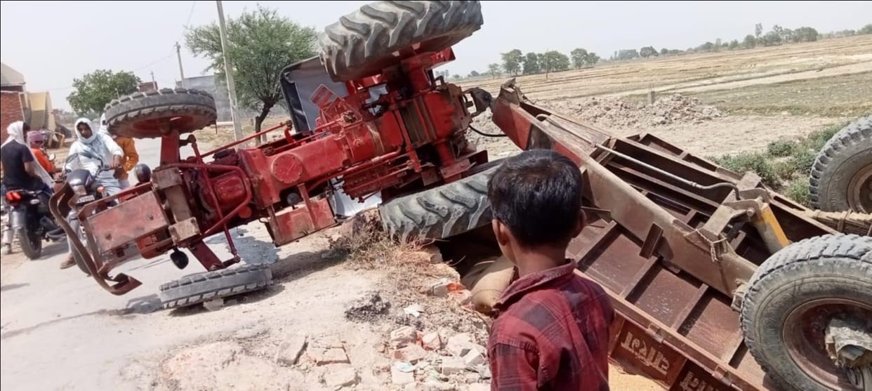 A tractor loaded with wheat overturned on a damaged culvert, with the driver narrowly escaping