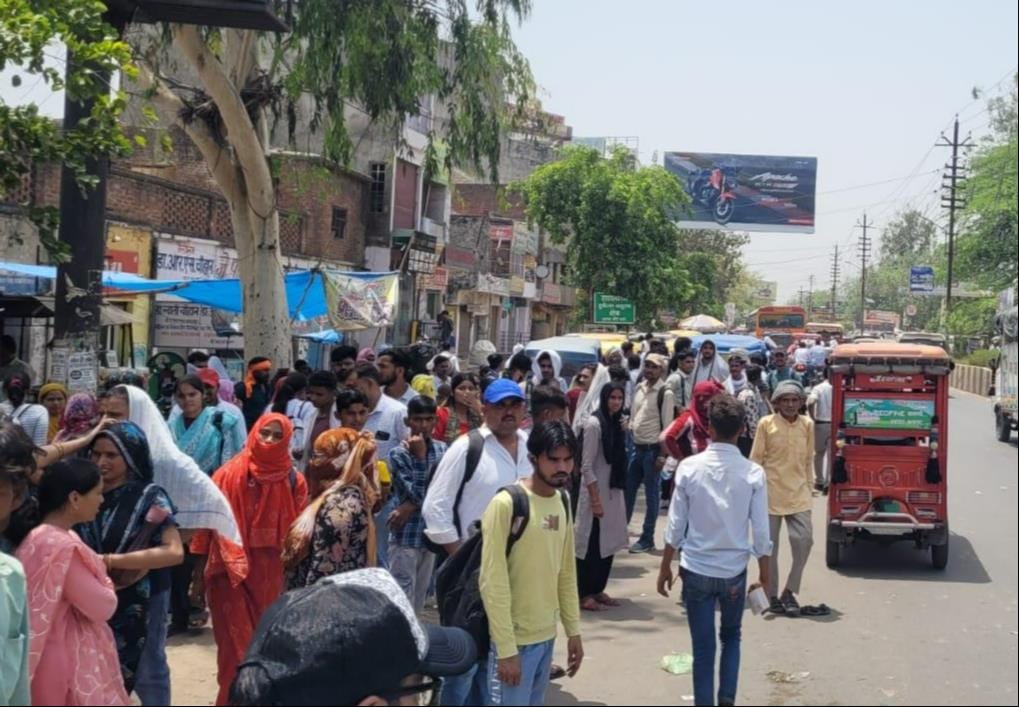 Crowd swarms bus stand after police recruitment exam; no buses in sight.
