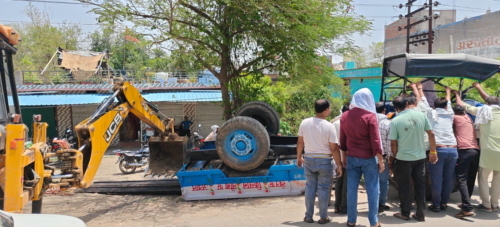 फोटो-02 कोंच के मलंगापुल पर पलटी पड़ी ट्रॉली व ट्रैक्टर को निकालते लोग। संवाद