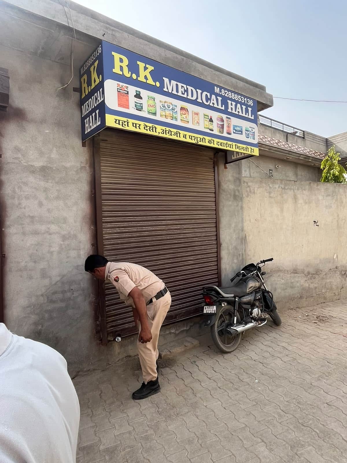 मेडिकल स्टोर पर लगी सील दिखाता पुलिसकर्मी। 