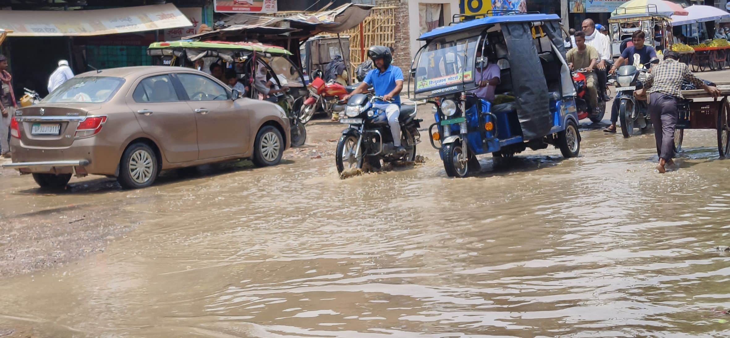 गल्लामंडी गेट के पास बारिश से सड़क पर हुए जलभराव के बीच से होकर निकलते वाहन। 