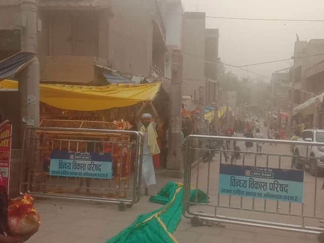 विंध्याचल में आंधी के दौरान दुकान के सामने लगी पन्नियां समेटता दुकानदार।- संवाद।