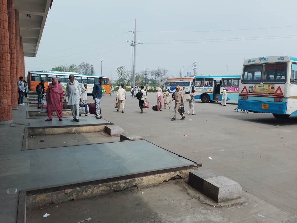 बस स्टैंड पर बस के इंतजार में खड़े यात्री। संवाद