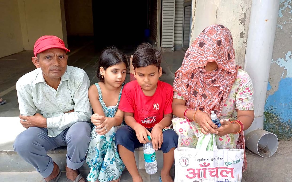 Sanitation worker sits on a protest at the municipal office with his family, carrying mosquito-killing insecticide.
