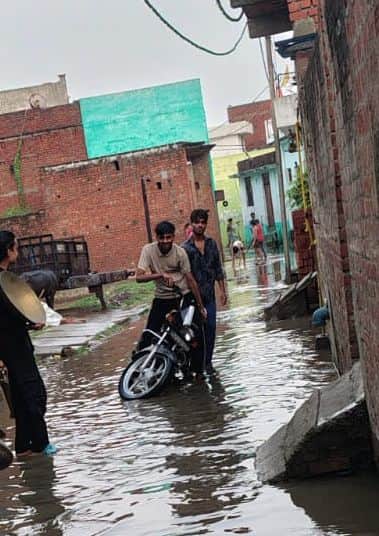 मीरानपुर कटरा में बारिश के दौरान फिसली युवकों की बाइक। संवाद
