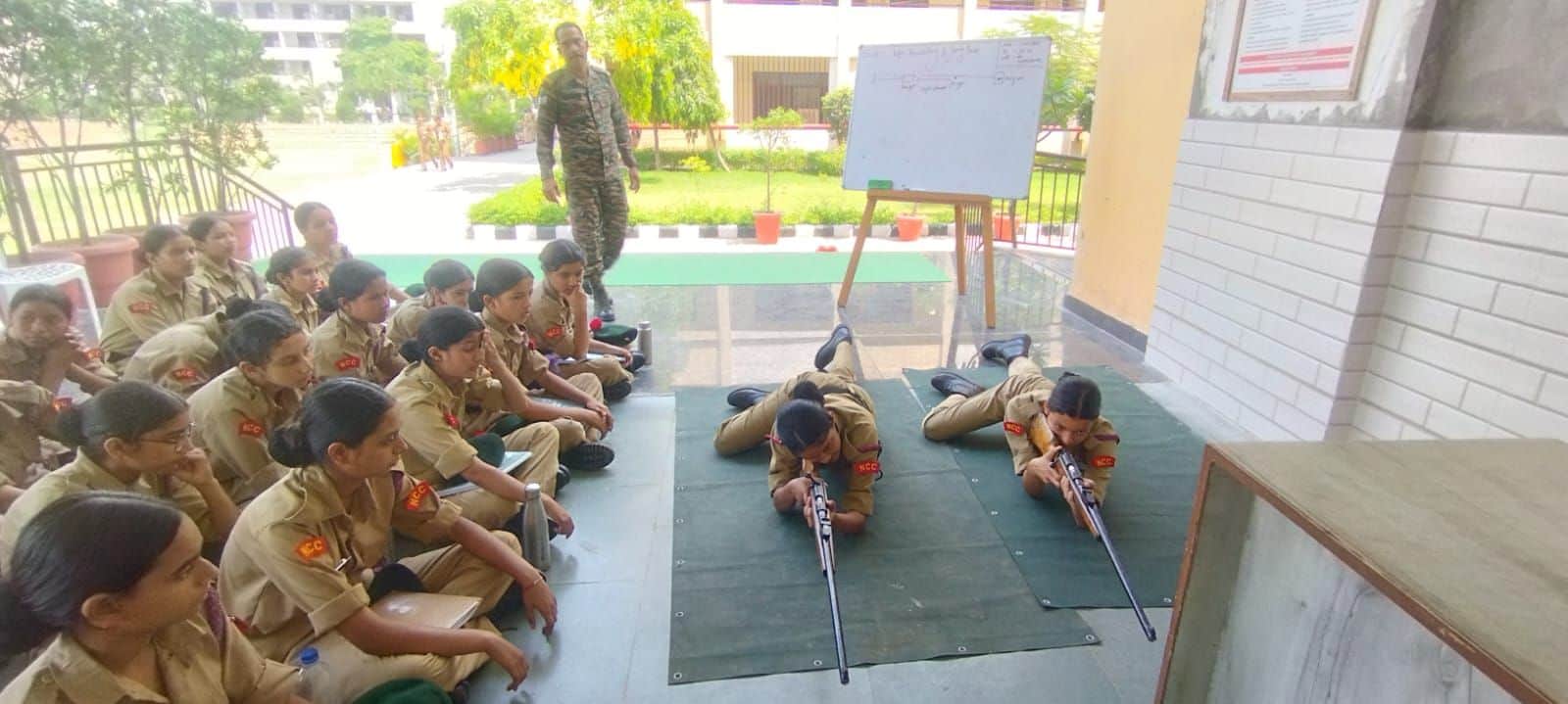 एनसीसी शिविर में फायरिंग पोजीशन का प्रशिक्षण प्राप्त करती कैडेट्स। संवाद