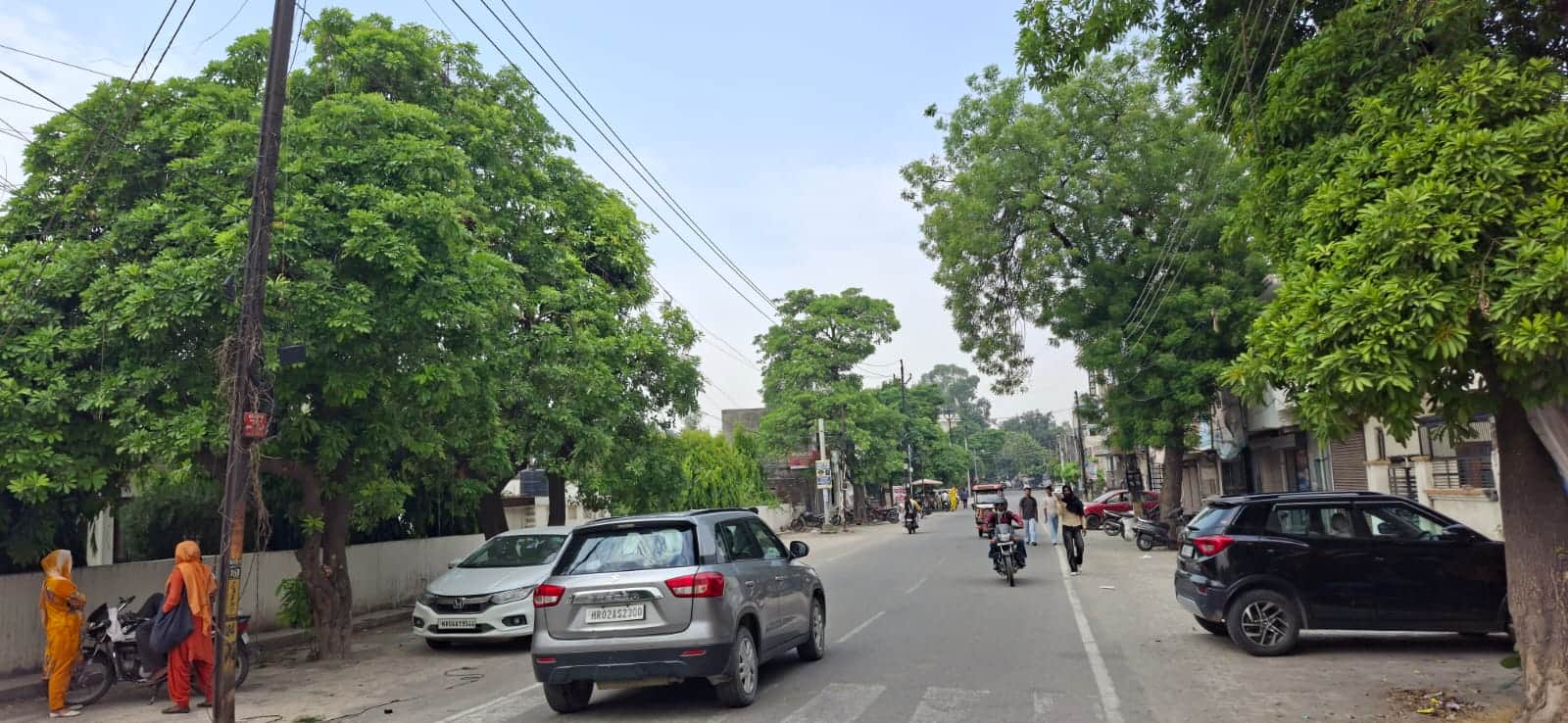 सुबह बादल छाने के दौरान बस स्टैंड रोड से गुजरते लोग। संवाद