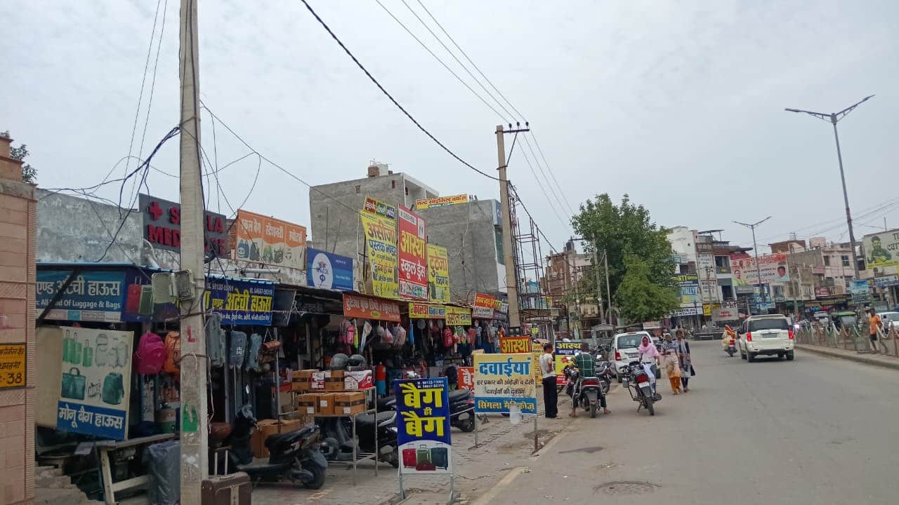 शहर के पालिका बाजार में दुकानों के आगे रखे बैनर व अन्य सामान। संवाद