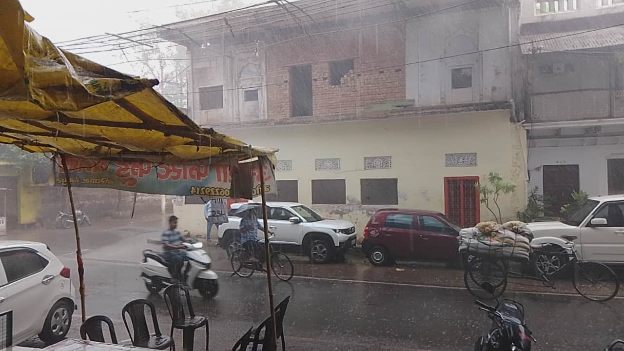 बारिश के बीच बरियाघाट मार्ग पर छाता ओढ़कर गुजरता साइकिल सवार।- संवाद।