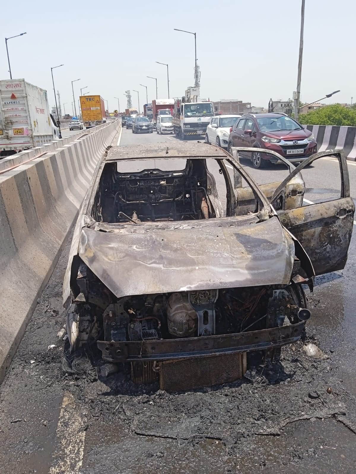 फ्लाईओवर पर आग लगने के बाद क्षतिग्रस्त हुई कार। अग्निशमन विभाग