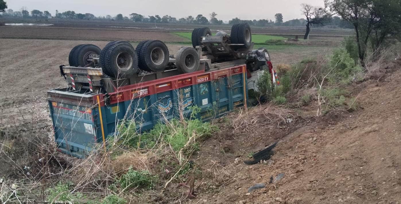 कंदवा के अमड़ा में सड़क किनारे गड्ढे में पलटा गिट्टी लदा डंपर। संवाद