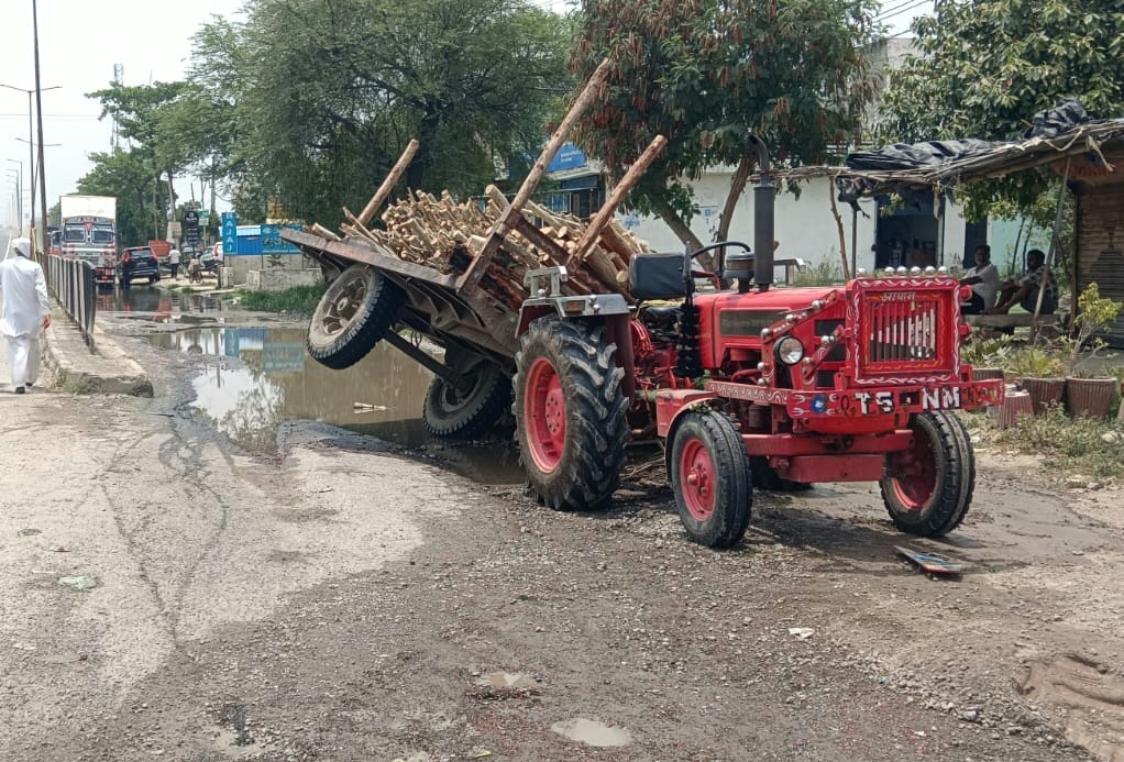 A trolley full of wood overturned on the service lane of the highway.