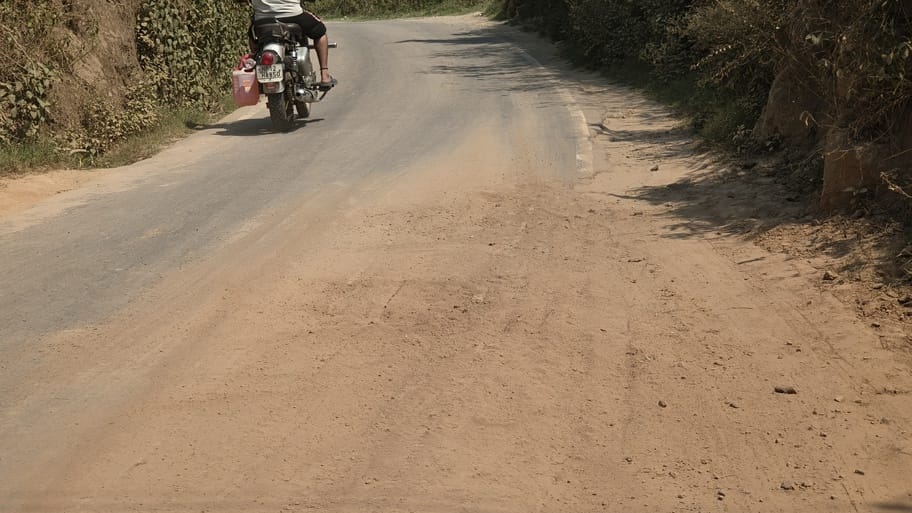 Potholes being filled with soil, yet the road surface breaks apart again by evening.