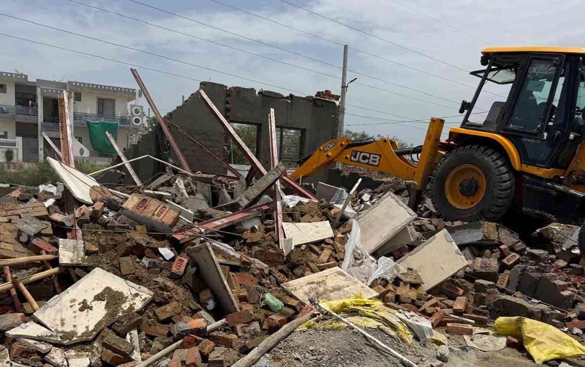 Three structures, two boundary walls, and a paved road network were demolished across 12.5 acres of land.