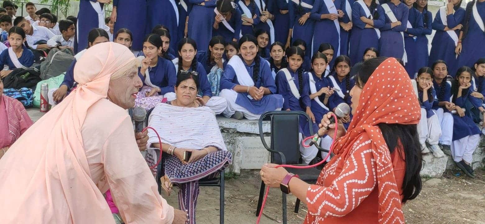 धनेटा स्कूल में लोक कलाकार नुक्कड़ नाटक के माध्यम से नशे के दुष्प्रभाव बताते हुए। स्रोत : जनसंप