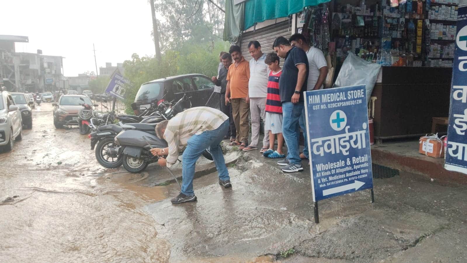मुख्य बाजार नादौन में बंद निकासी नालियों में फंसे कचरे को डंडे से हटाता दुकानदार। स्रोत जागरूक 