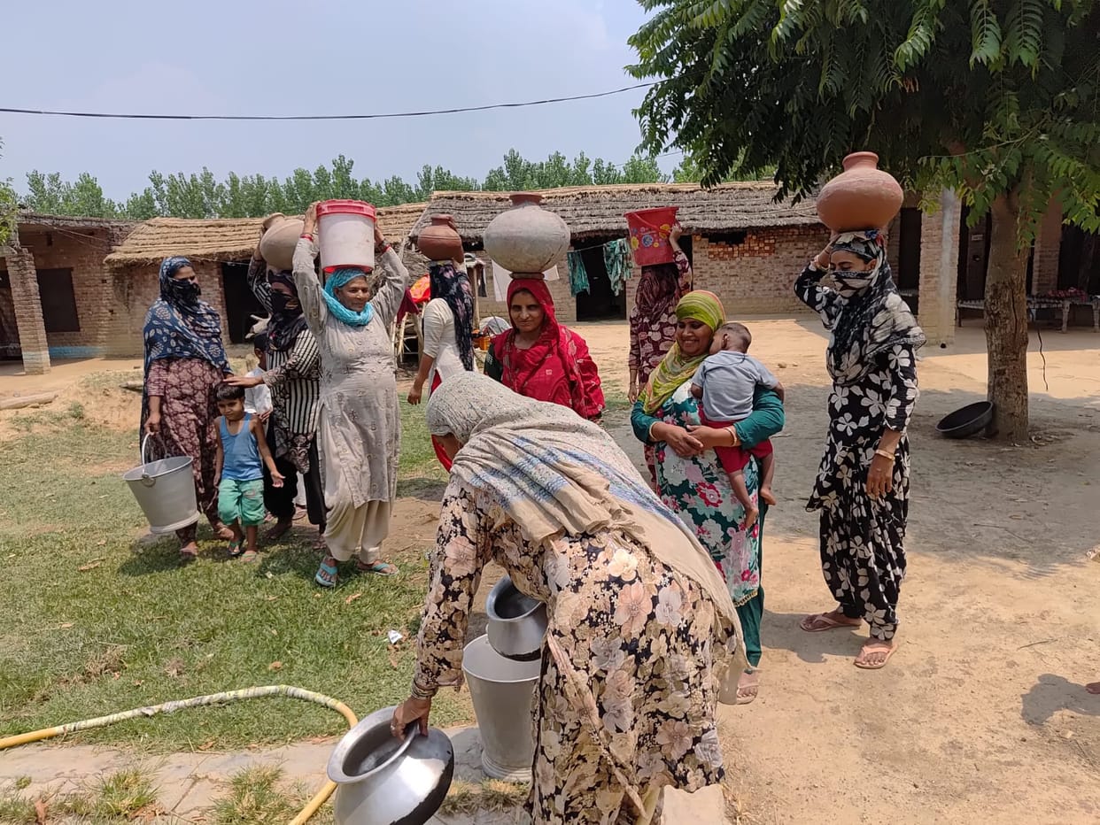 Women are carrying water on their heads from a distance