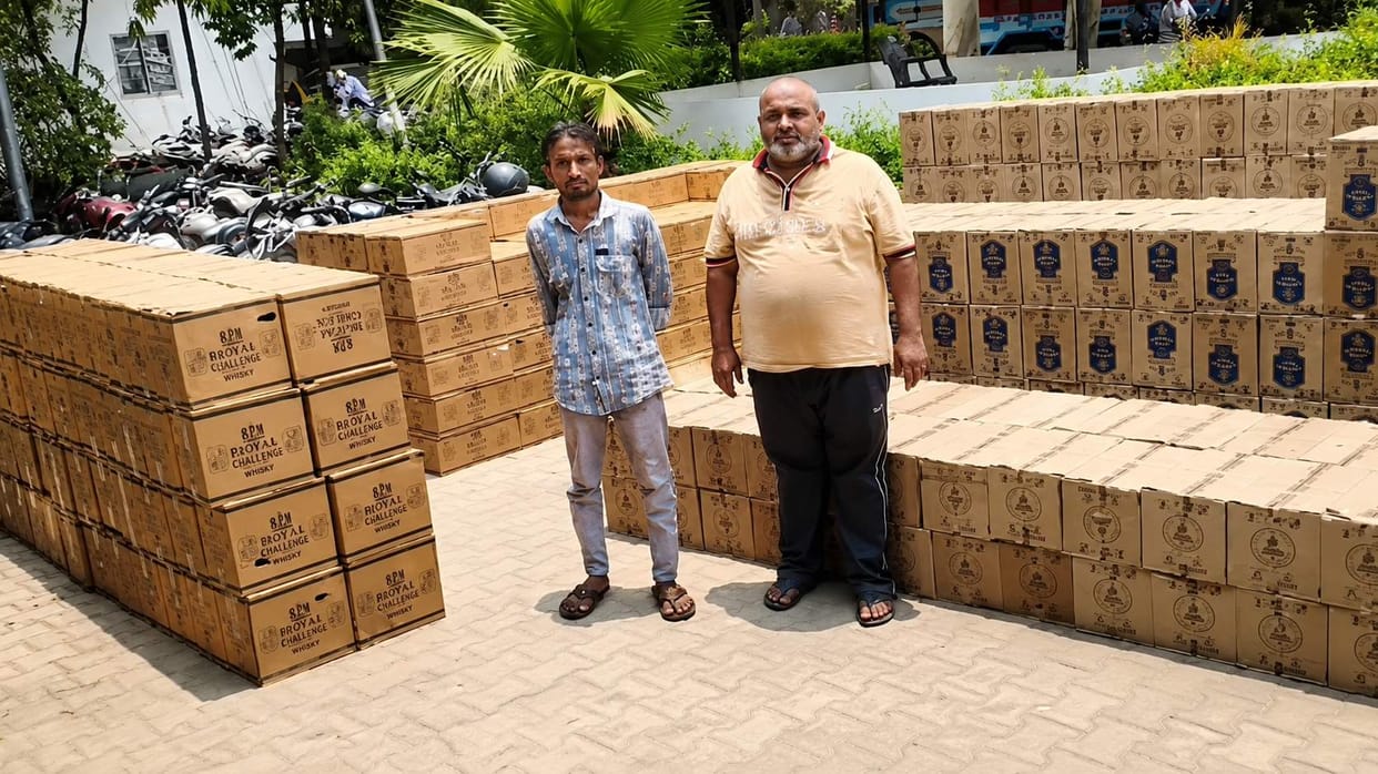 663 cartons of Indian-made foreign liquor (IMFL) seized from a truck's secret cabin; two arrested.