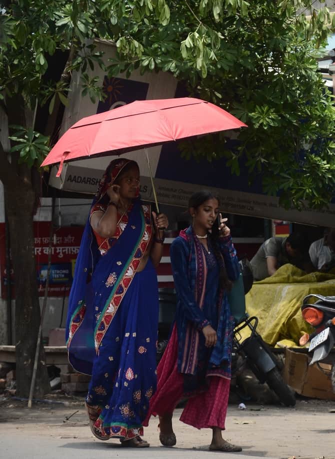 चिलचिलाती धूप से बचने के लिए   छतरी लगाकर निकली महिला। संवाद