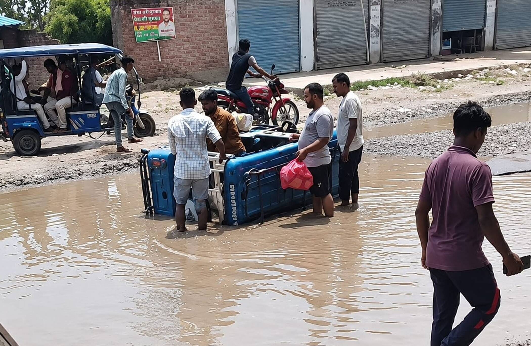 फोटो-23-जीटी रोड पर बने गड्ढे में भरे पानी में पलटा ई रिक्शा। संवाद