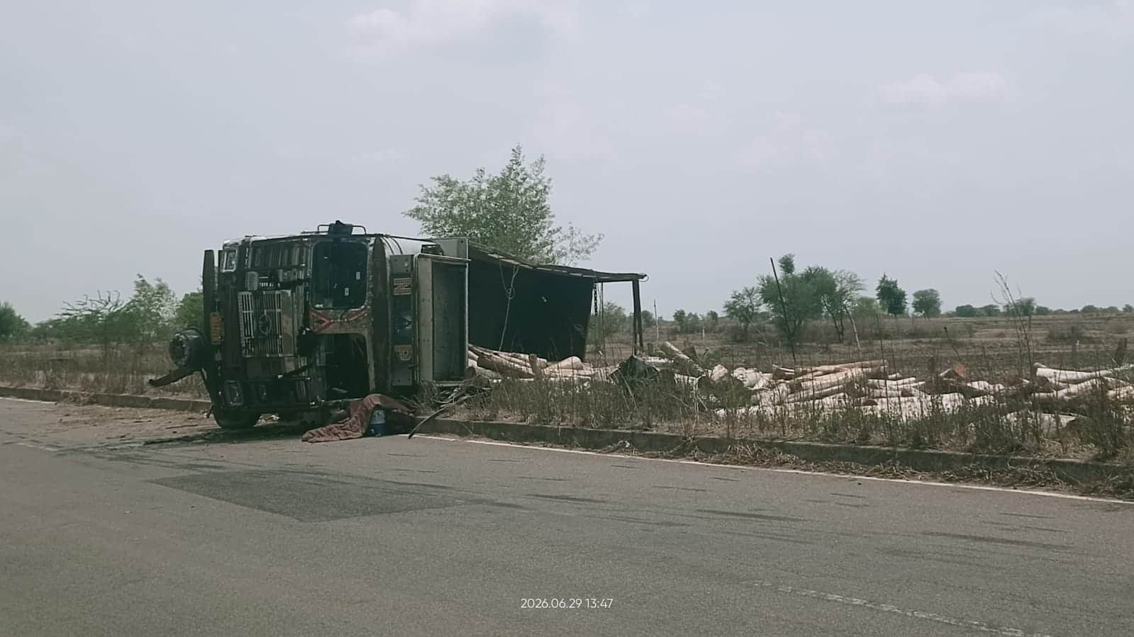 हरीपुर गांव के पास पलटा पड़ा ट्रक व फैली लकड़ियां। संवाद