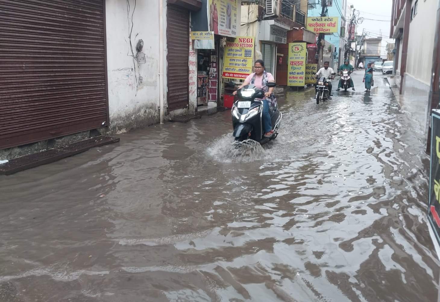 07 -आर्दश ग्राम में हुए जलभराव के बीच से होकर गुजरते दोपहिया वाहन चालक।संवाद