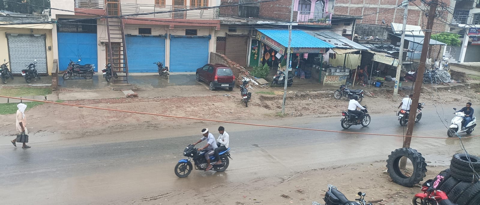  भिनगा में बारिश के दौरान भीगते हुए जाता बाइक सवार।