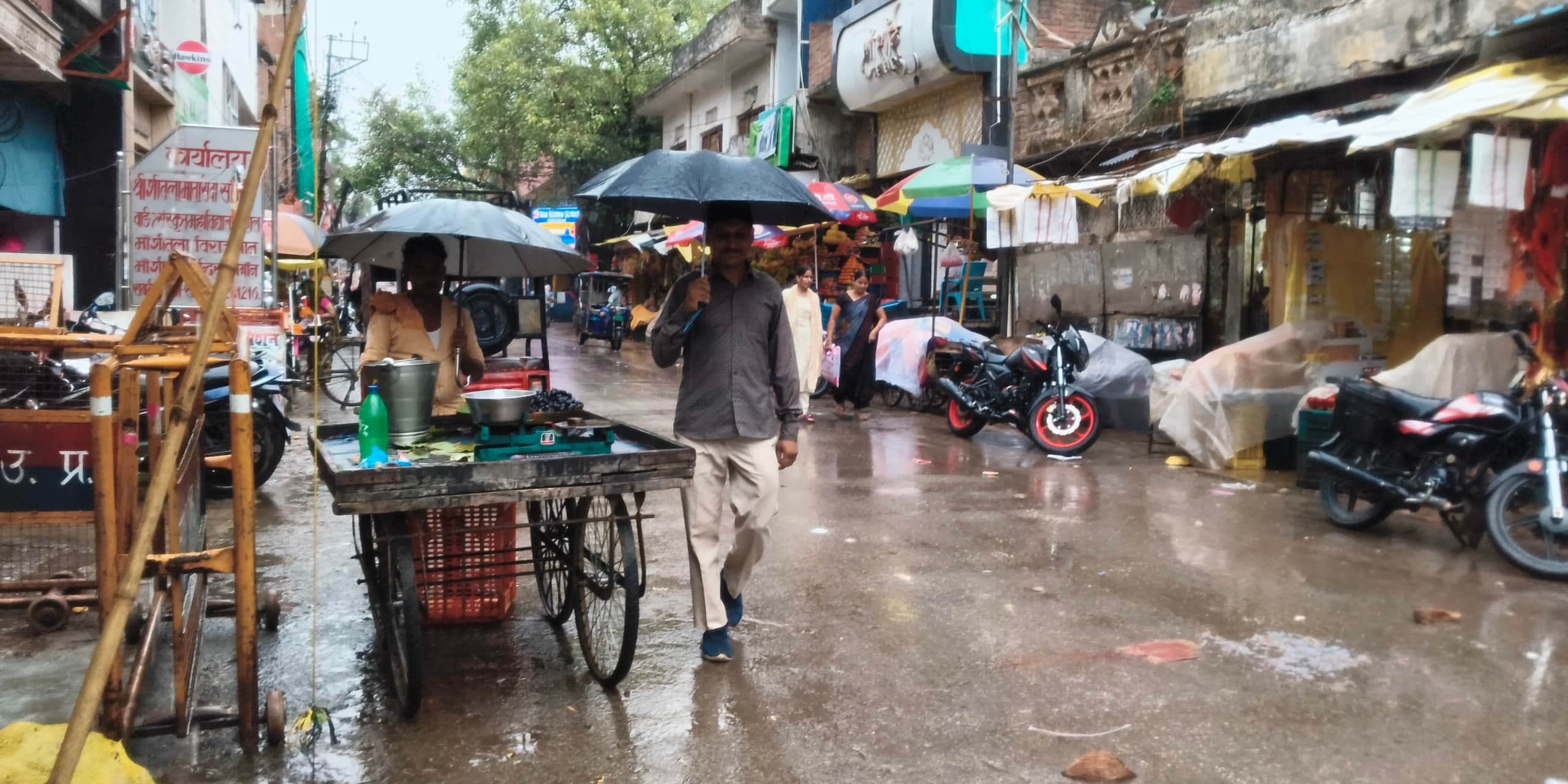 रॉबर्ट्सगंज में हल्की बारिश में छाता लगाकर निकले लोग।संवाद