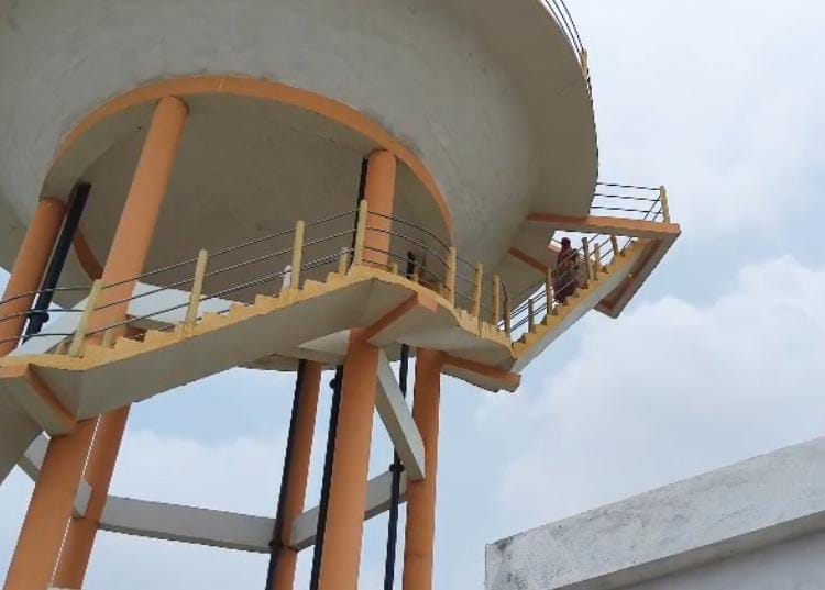Woman angered by land grabbing climbs water tank to demand action.