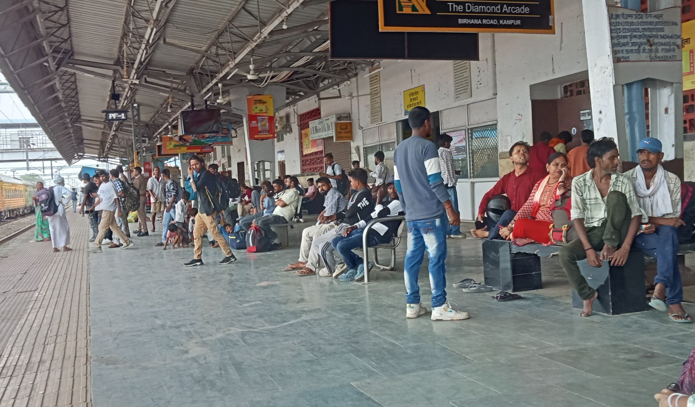 रेलवे स्टेशन पर ट्रेन का इंतजार करते लोग।