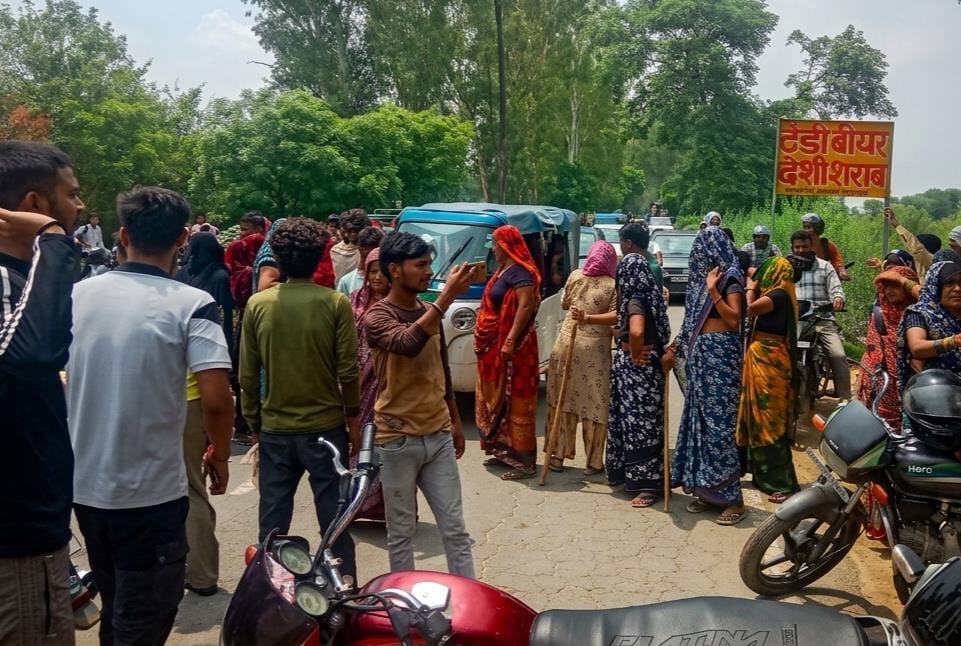 Women protest against liquor shop, block the road.