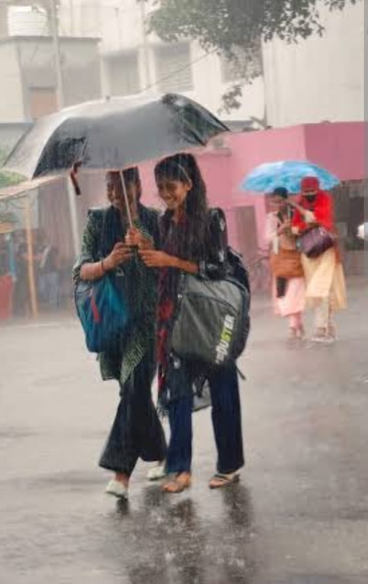 बारिश में छाता लगाकर जाती युवतियां - संवाद