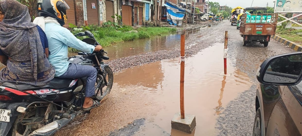 Road caves in near Mamon village on the Bareilly four-lane highway; vehicles getting stuck in deep potholes.