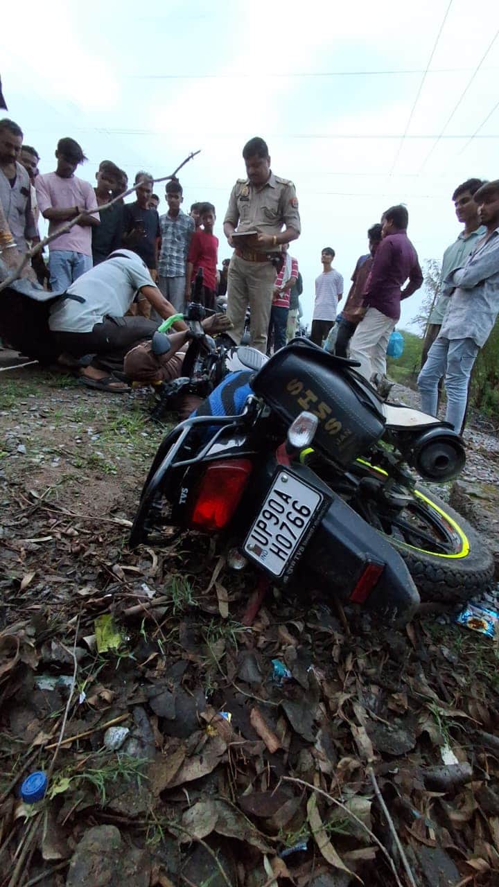 घटनास्थल पर पड़ी बाइक व लोगों के साथ खड़ा पुलिसकर्मी। संवाद