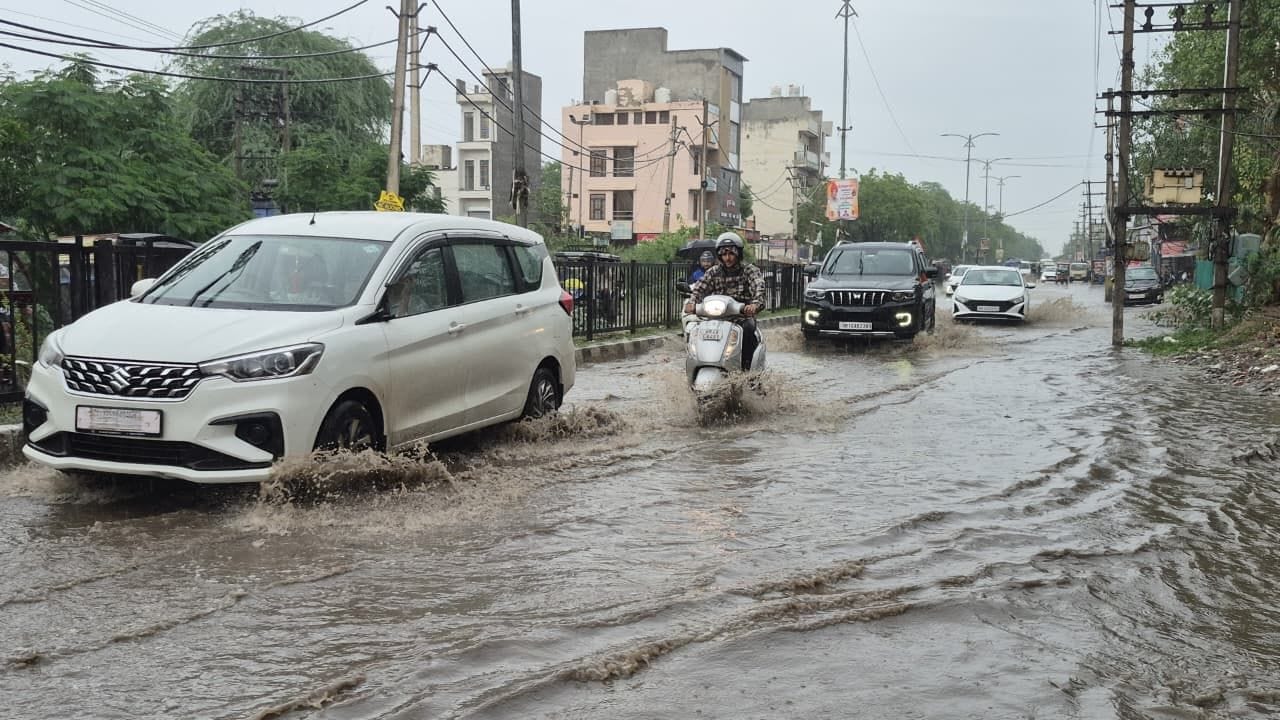 शहर में रोहतक रोड पर जमा  बारिश के पानी  से गुजरते वाहन।