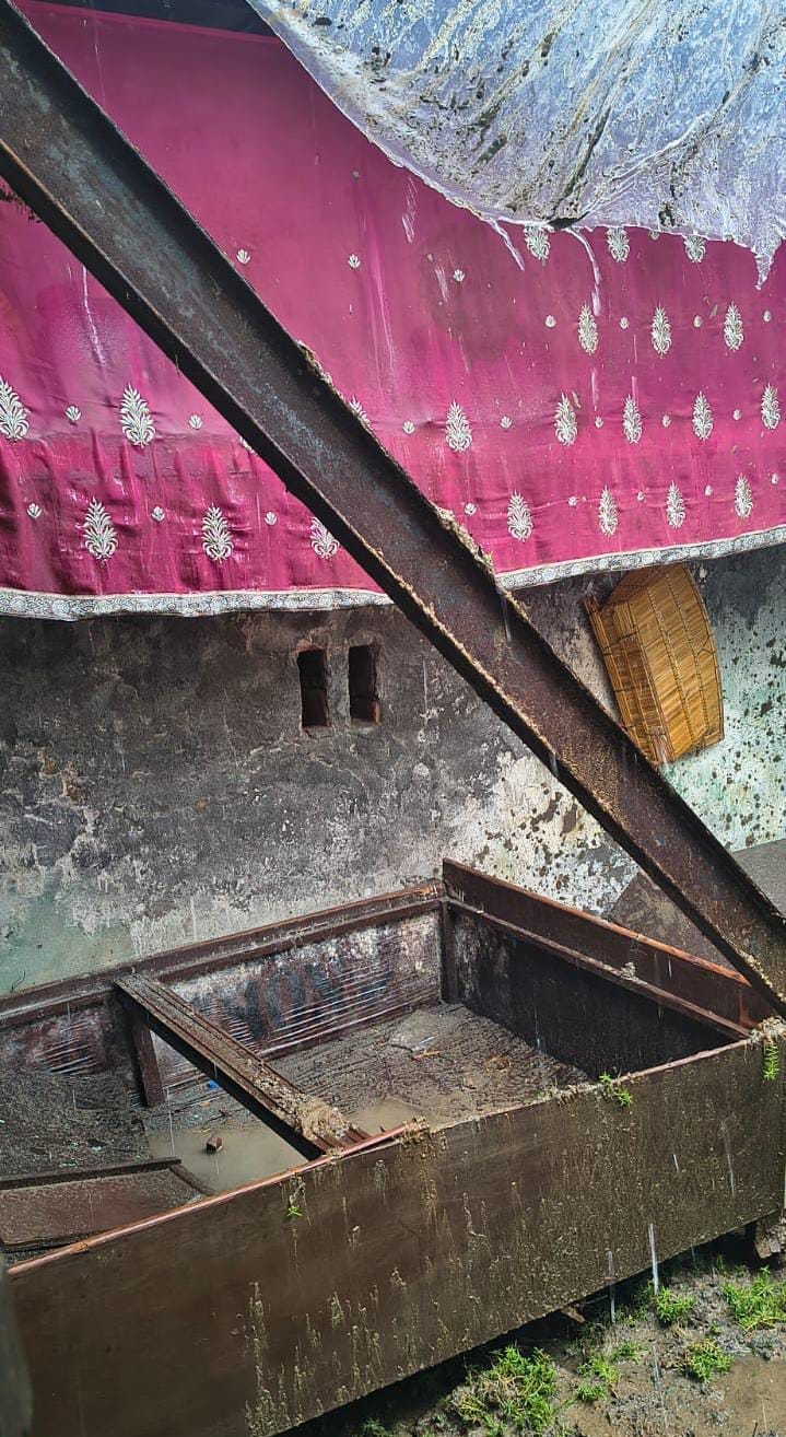 House collapses in the rain; belongings buried under the debris.