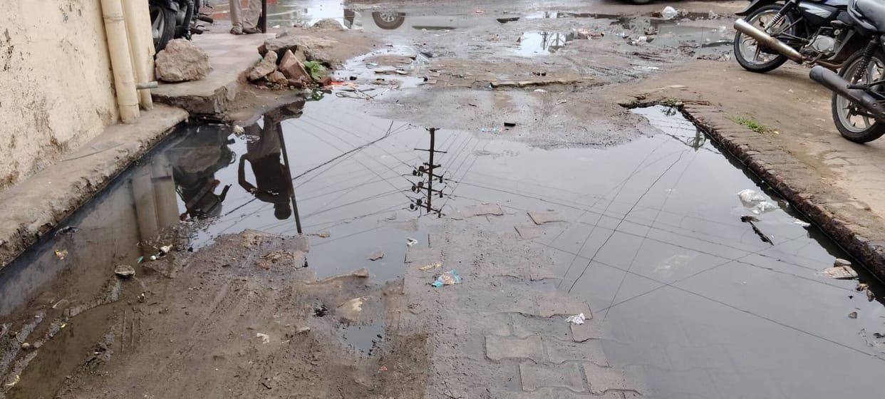 Accumulation of dirty water in the street troubles pedestrians and shopkeepers.