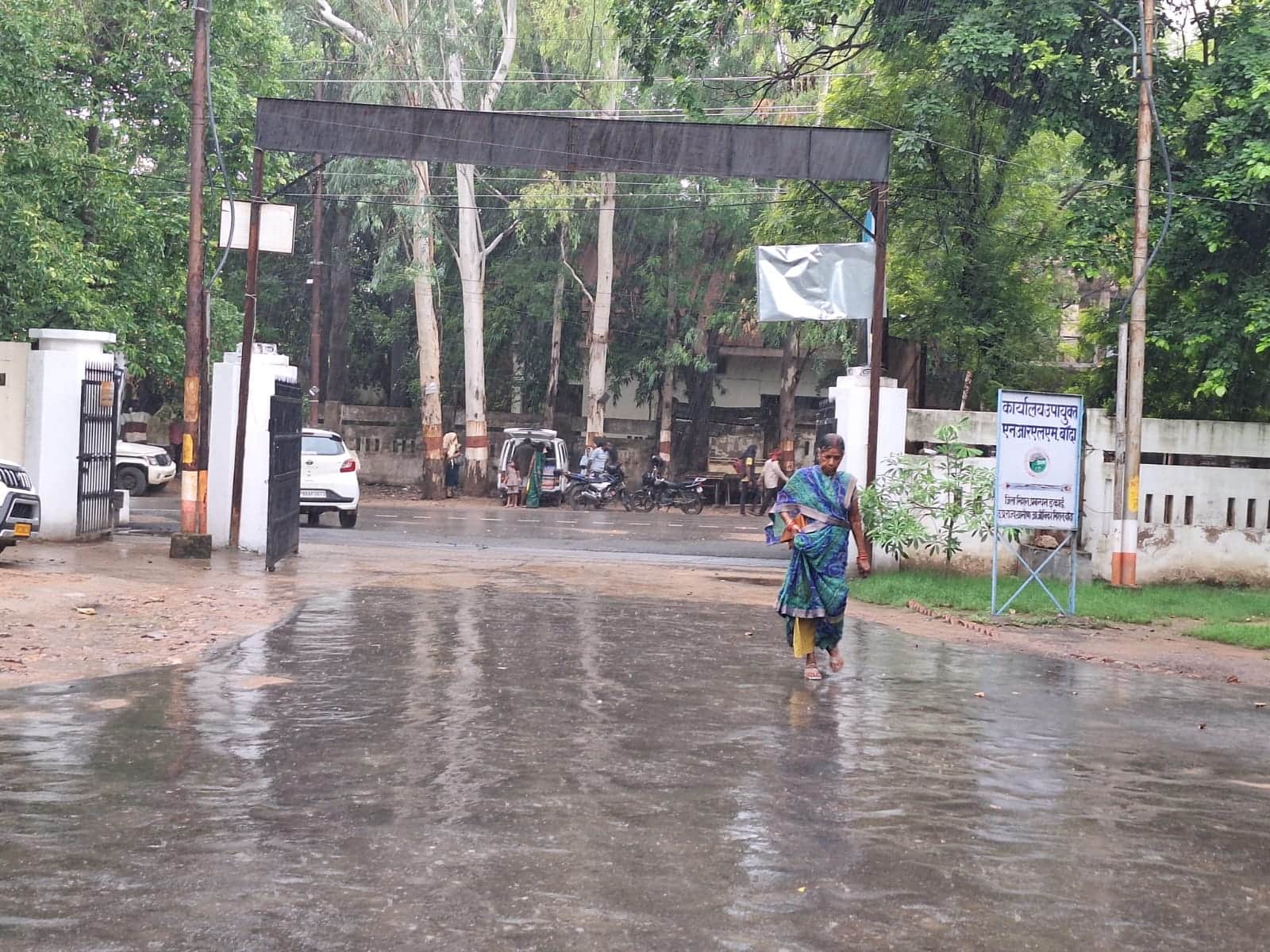विकास भवन में बारिश के बीच जाती महिला। संवाद