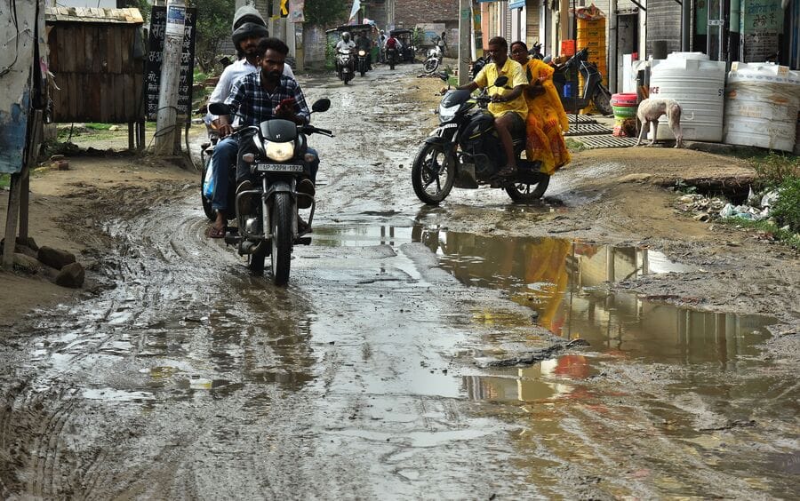 Rainwater accumulates on damaged road; commuters face inconvenience.