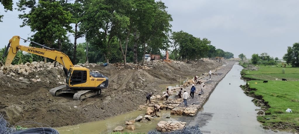 River begins flowing right against the dam; slope and patching work remains incomplete.