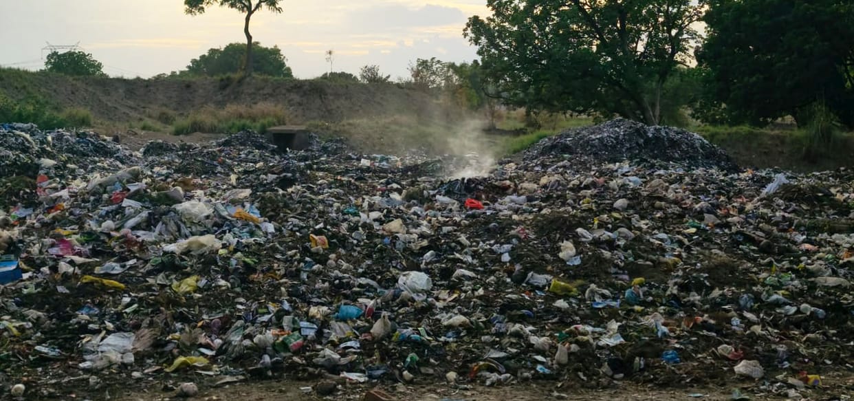 Rainwater accumulates at MRF center; garbage being burned outside.