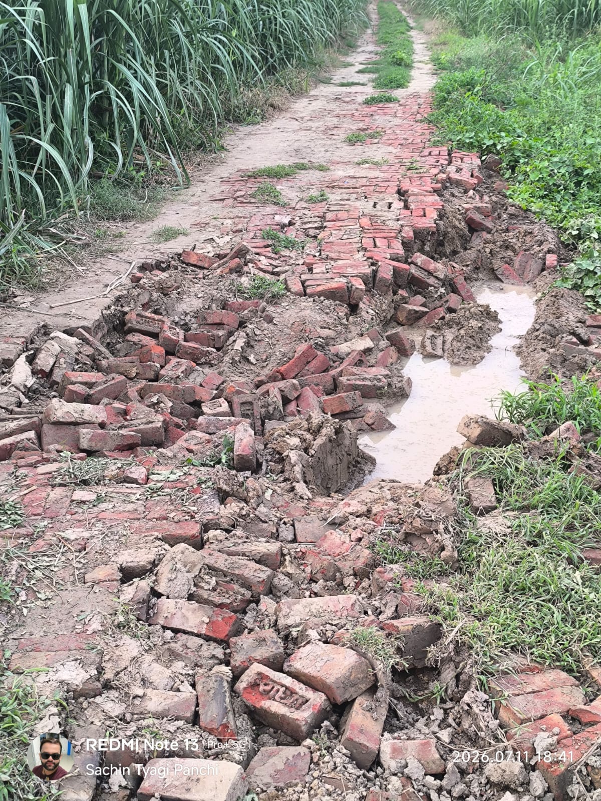 Road washed away by rain in Panchi; funeral procession passes along railway tracks.