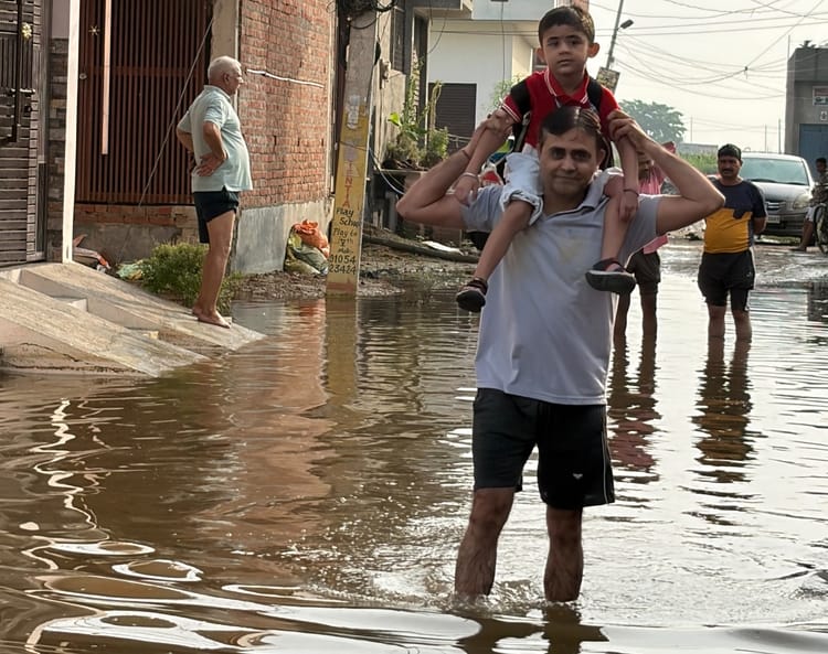 Family members carrying children on their shoulders amidst waterlogging.