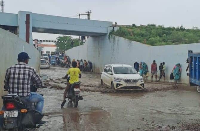 फोटो23कासगंज में एटा रोड पर नदरई रेलवे अंडर पास में हुए जलभराव के बीच से गुजरते वाहन व लोग। स