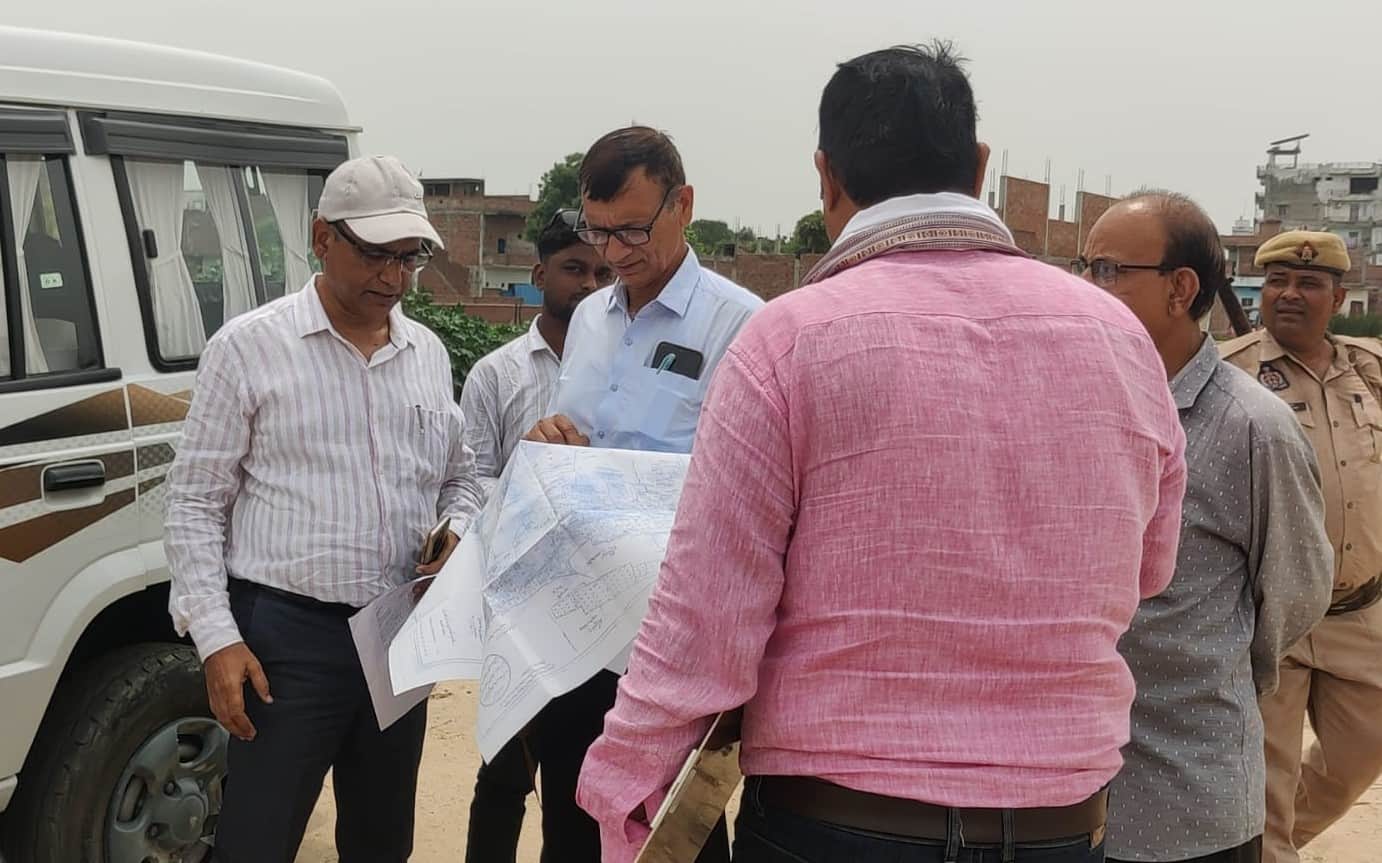 गोपीगंज तालाब पर नक्शा देखते राजस्व विभाग की टीम। संवाद