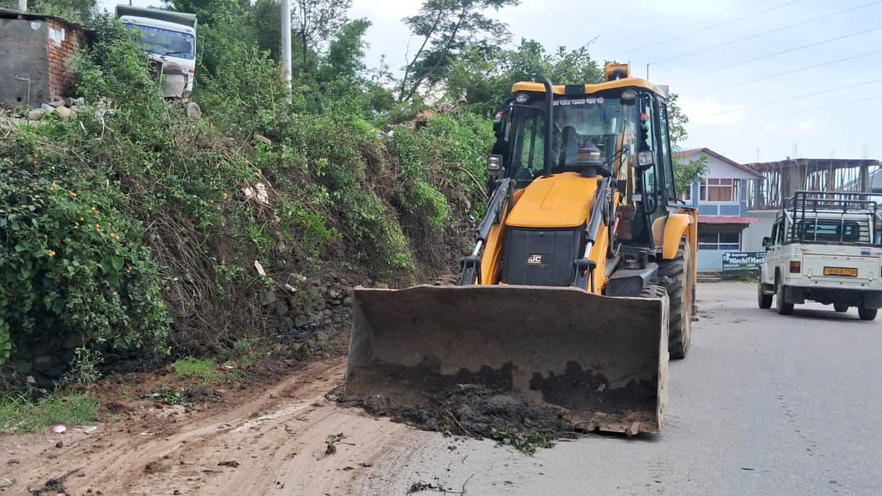 Machinery engaged in cleaning highway-side drains and removing debris.