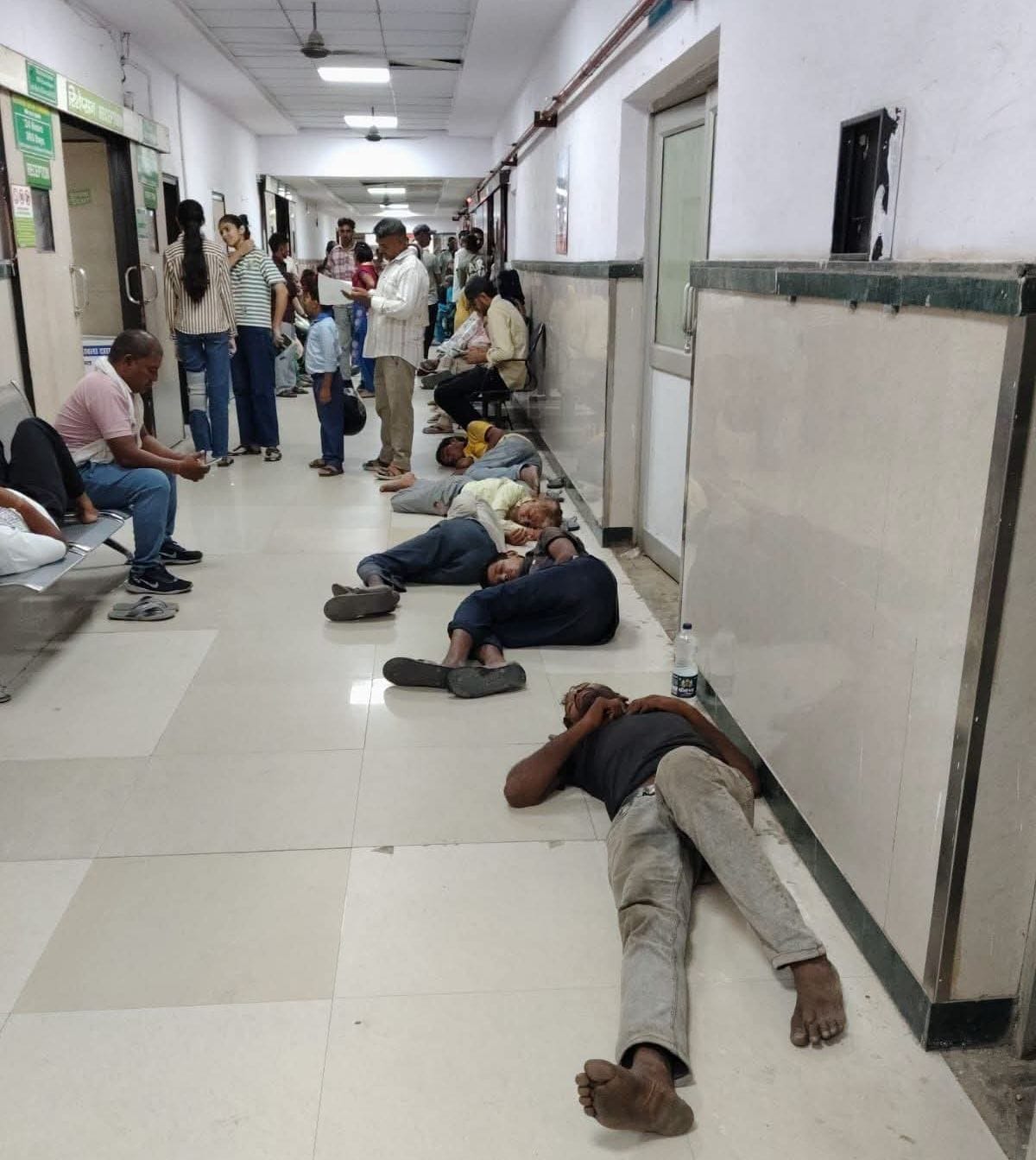 नागरिक अस्पताल में बैठने की जगह नहीं मिलने पर फर्श पर लेटे मरीज। 
